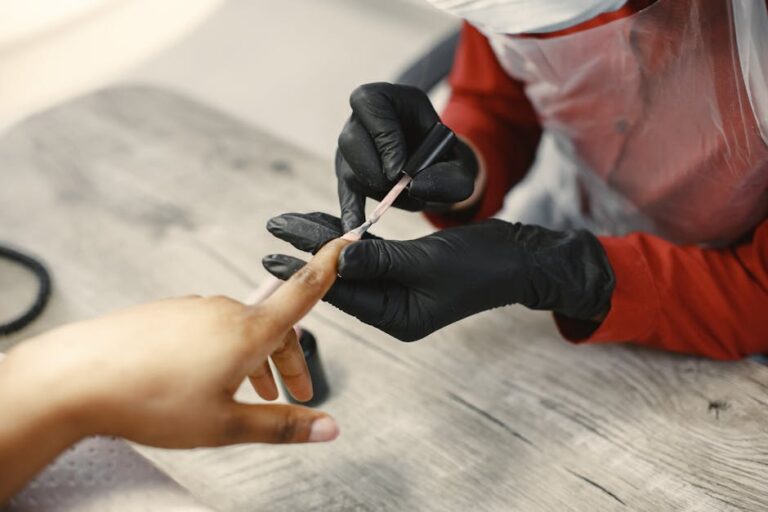 A nail artist carefully applies nail polish to a client's nails in a salon setting, using precise techniques.